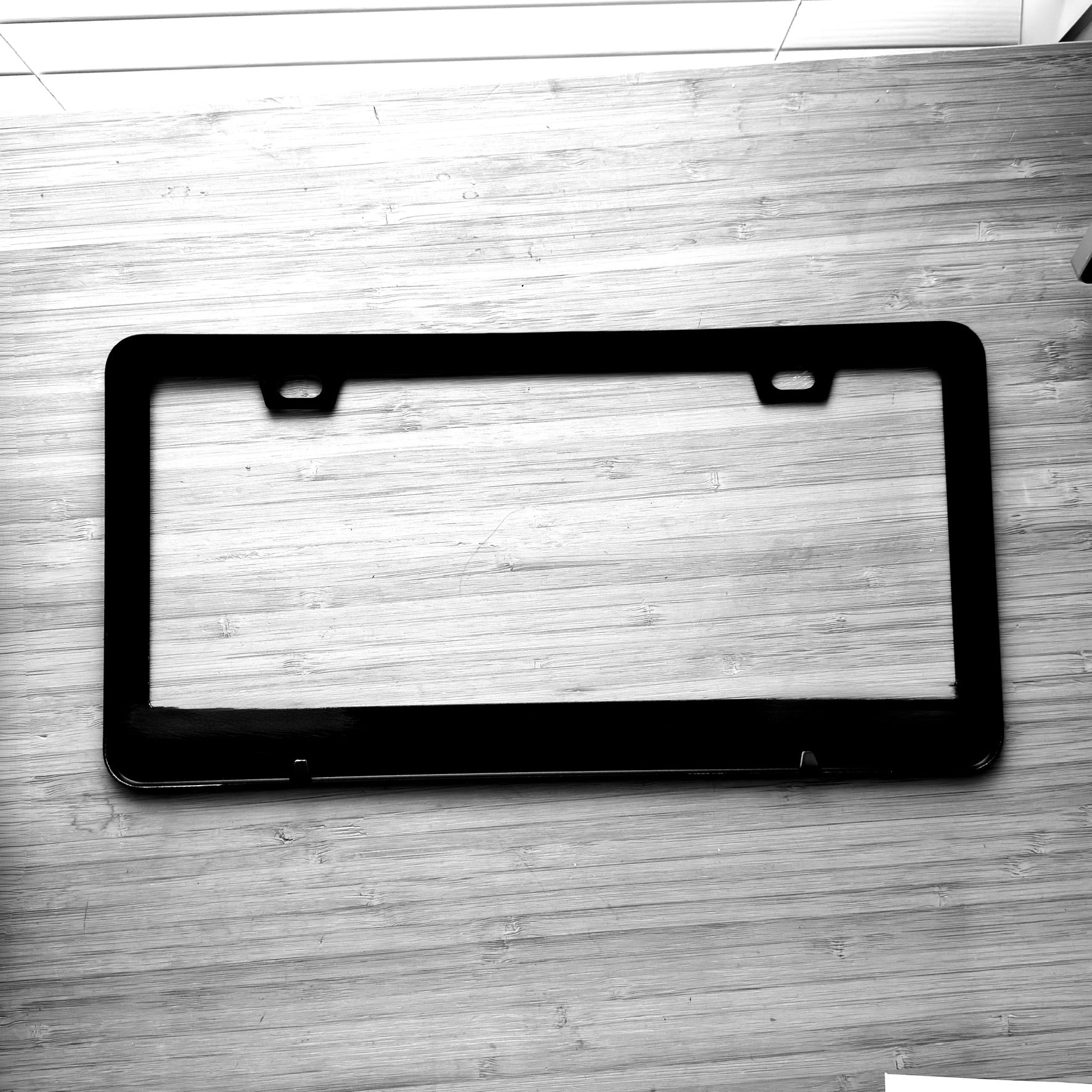 Black license plate frame on a wooden surface
