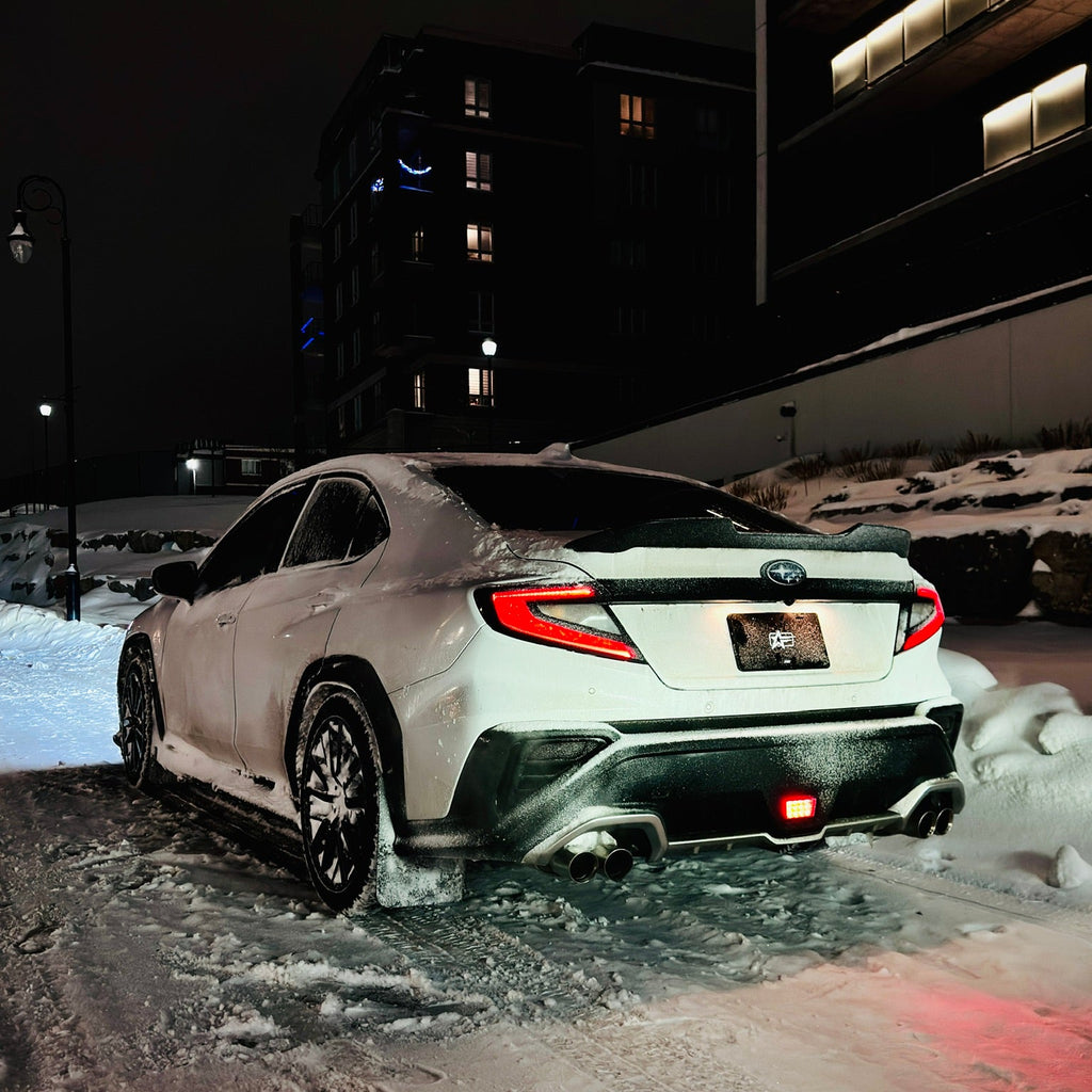 White car stuck in snow at night with buildings in the background