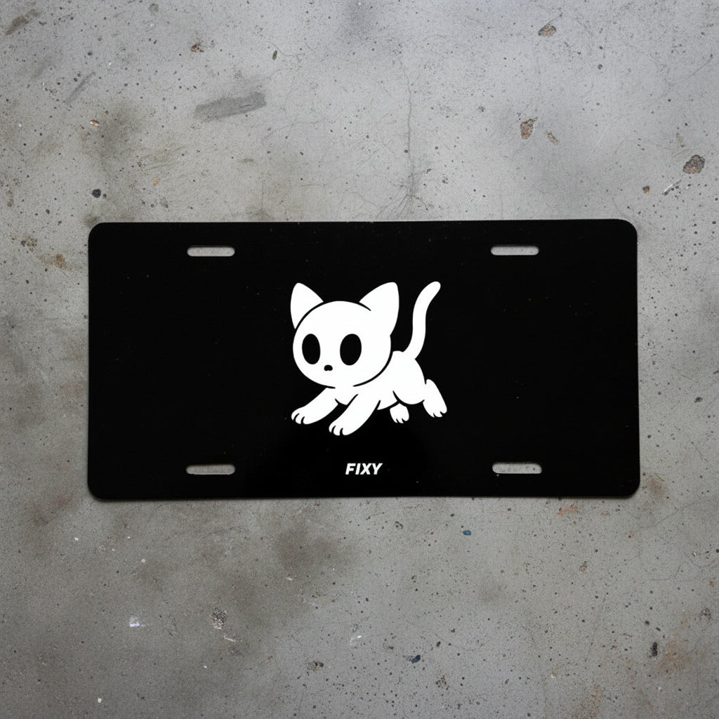 Black license plate with a white cat illustration and 'FIXY' branding on a concrete surface.