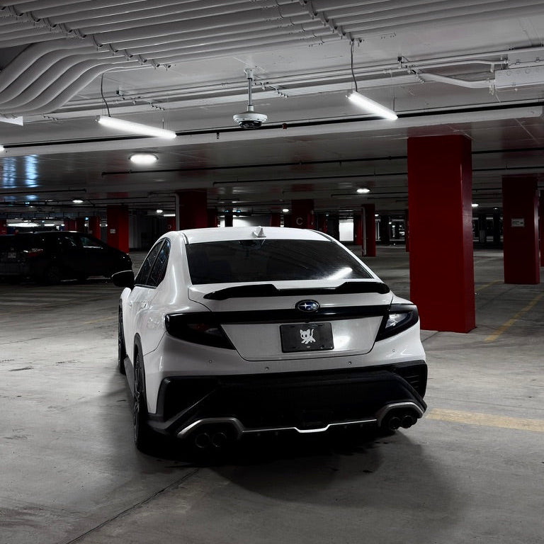 White car parked in a dimly lit underground parking garage.