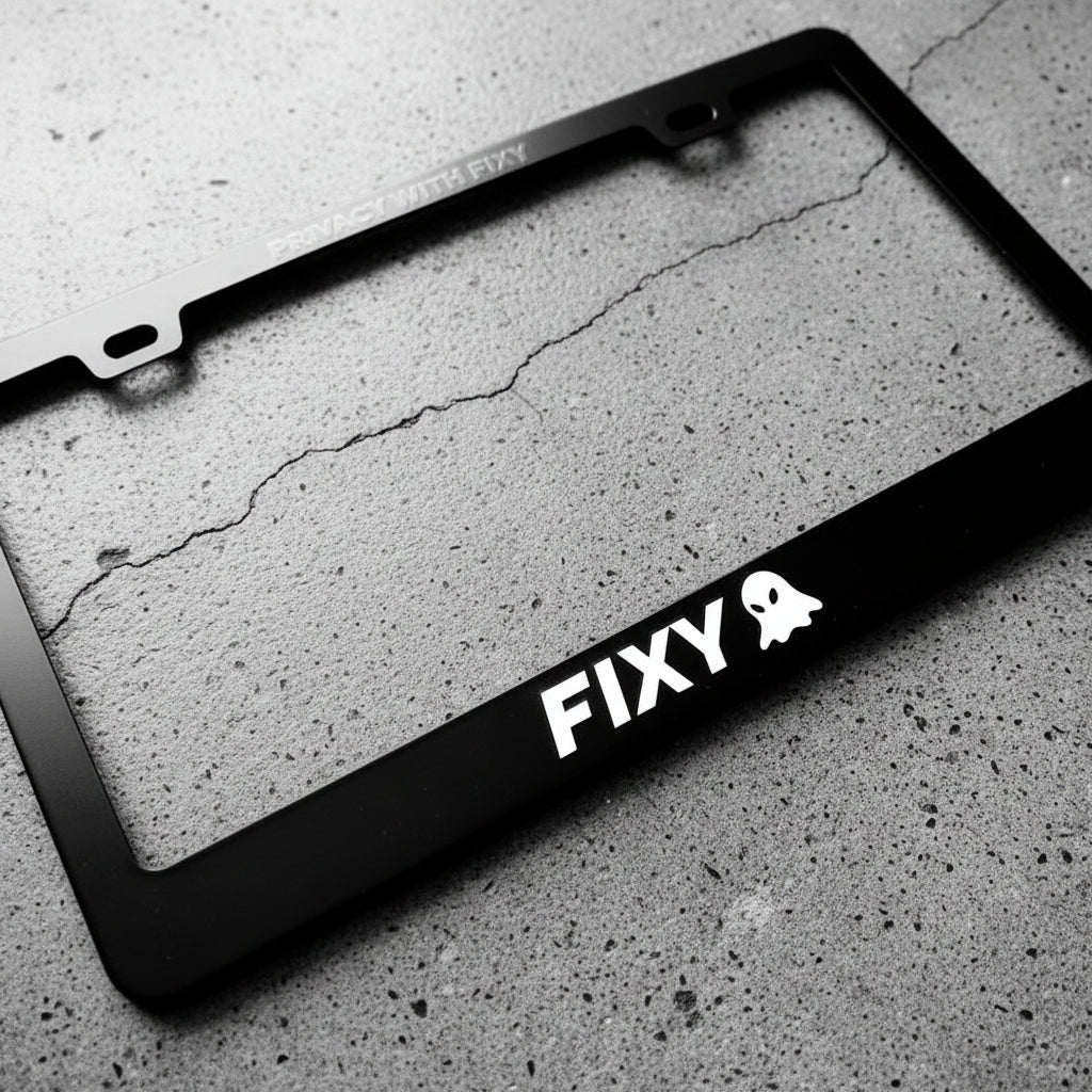 Black license plate frame with 'FIXY' and a ghost logo on a concrete surface