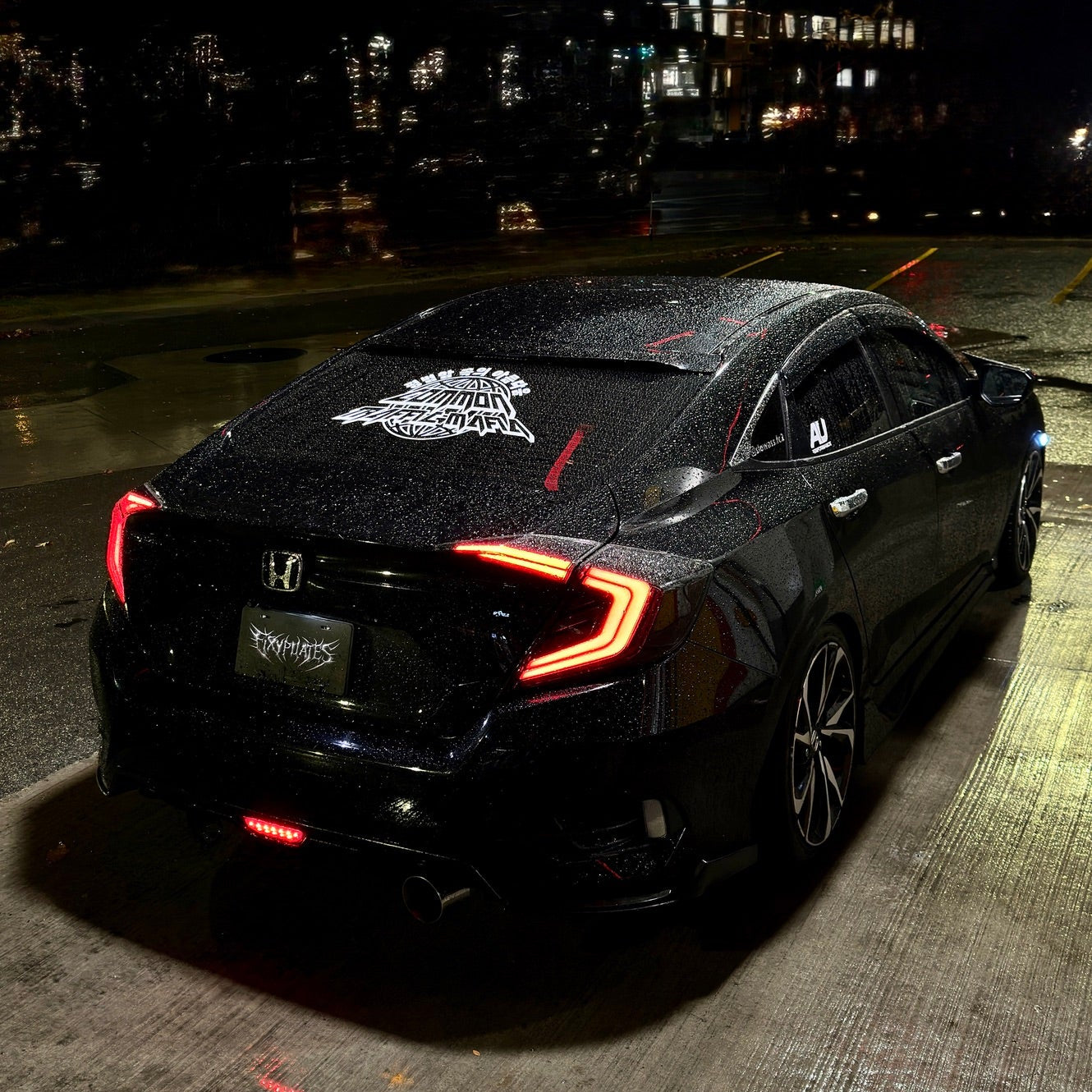 Black car with a distinctive logo on the hood at night.