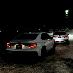 Two cars on a dark road with taillights on