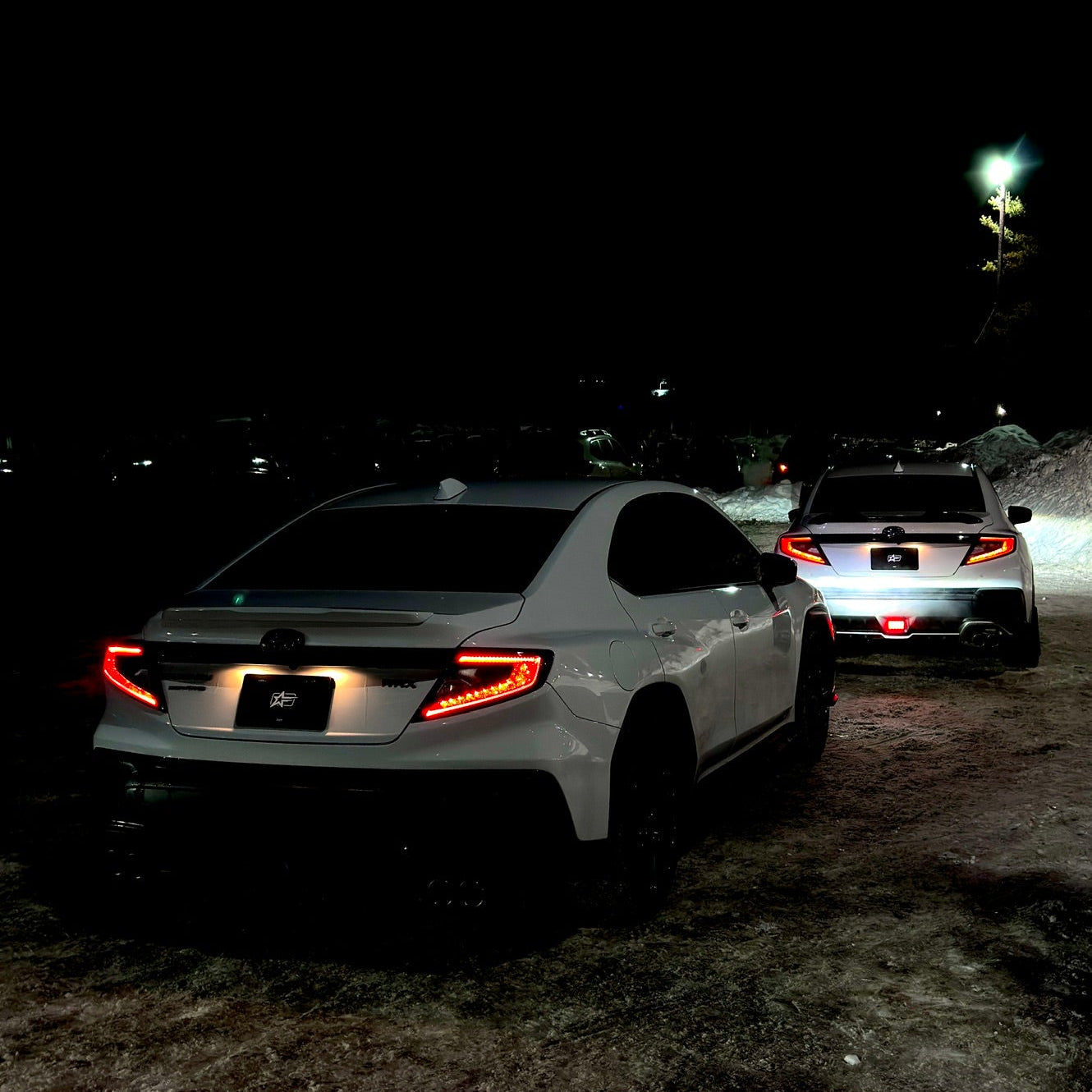 Two cars on a dark road with taillights on