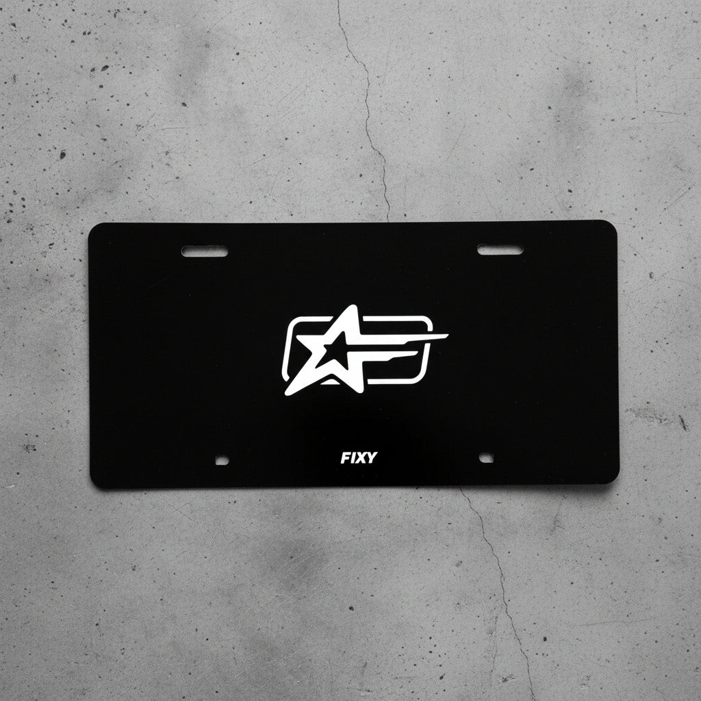 Black license plate with a white logo and 'FIXY' text on a wooden surface