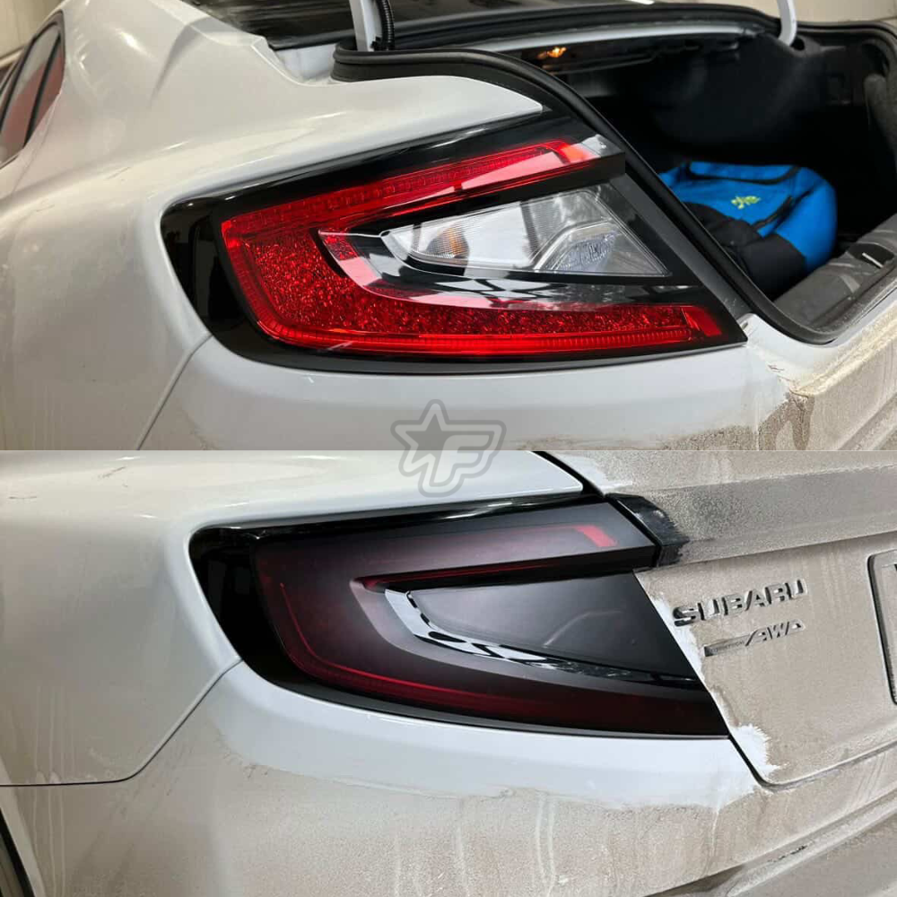 Close-up of a car's taillight and Subaru logo on a white car.