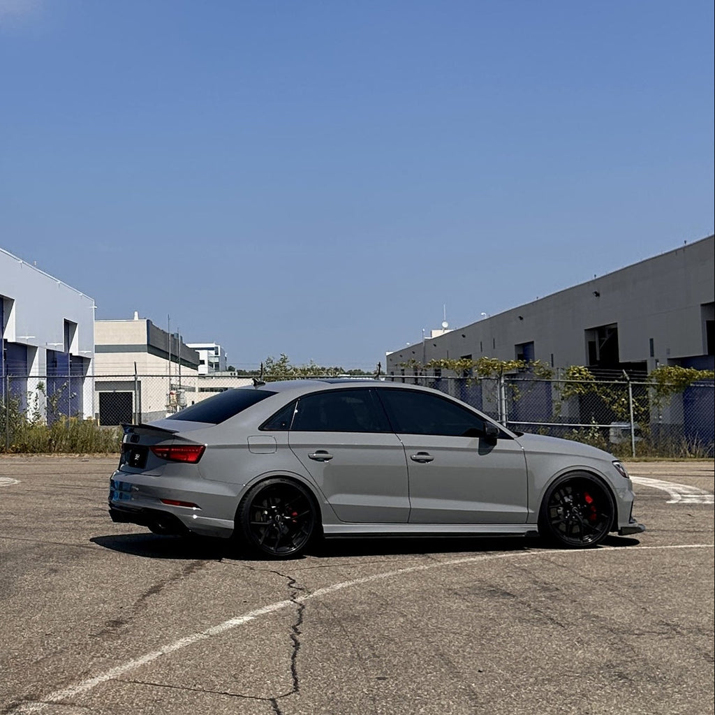 Gray car parked in a lot with buildings in the background
