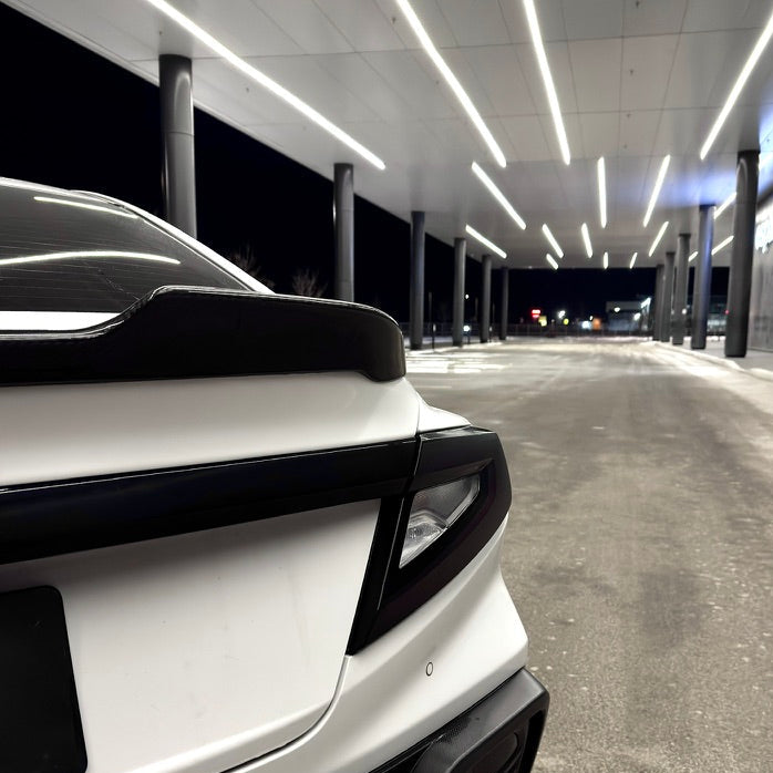 White car with black accents in a modern indoor parking garage.