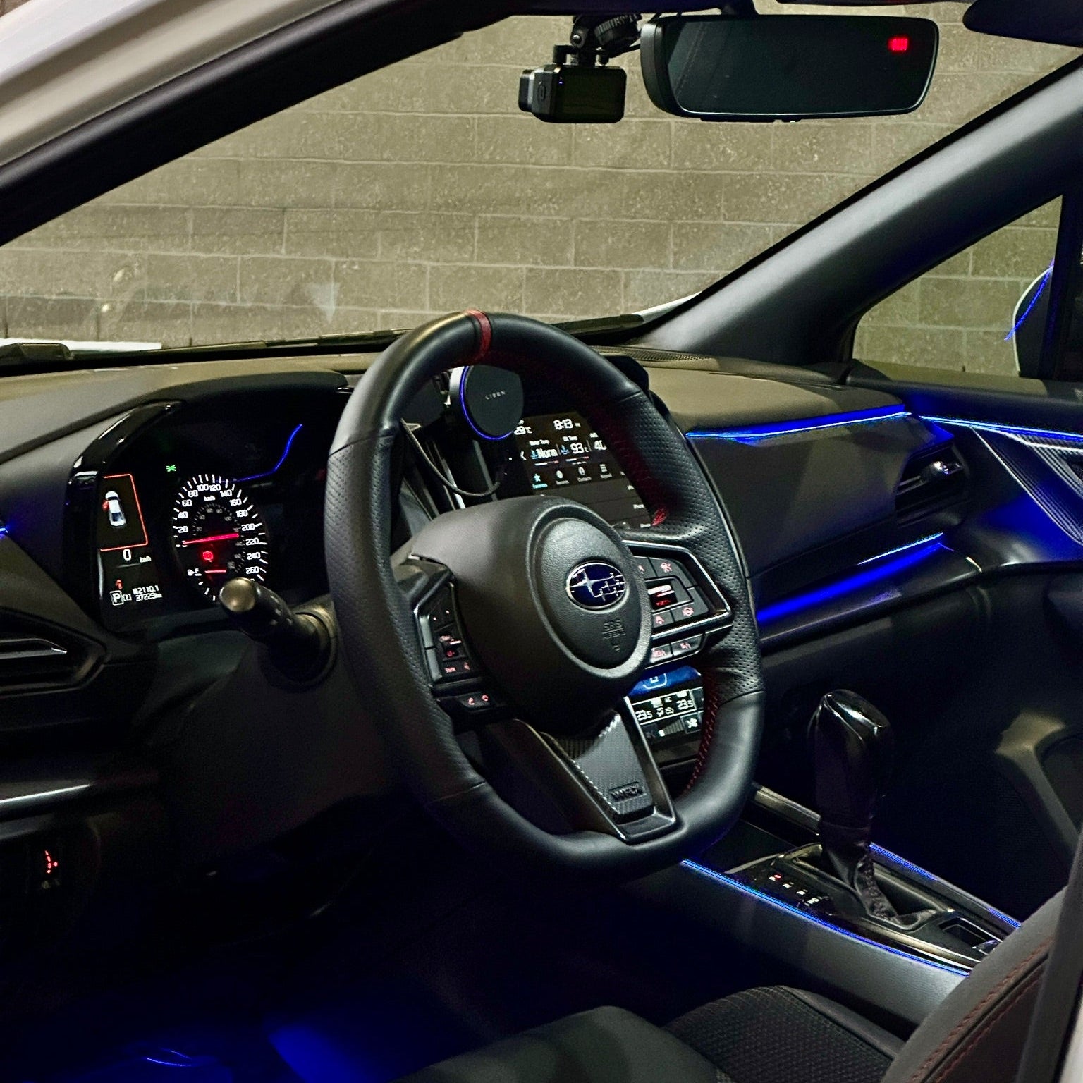 Car interior with steering wheel and dashboard against a brick wall background