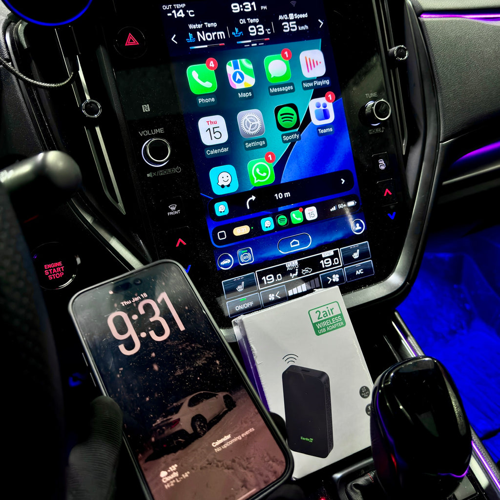 Car dashboard with smartphone, air freshener, and digital display showing app icons.