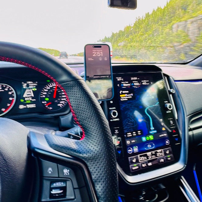 Car interior with digital dashboard display, steering wheel, and smartphone mounted on the windshield.