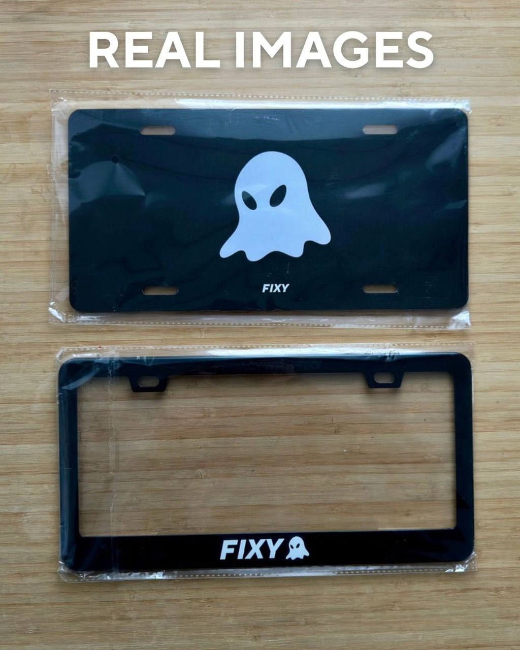 Two license plate frames with a ghost design and 'FIXY' branding on a wooden surface.