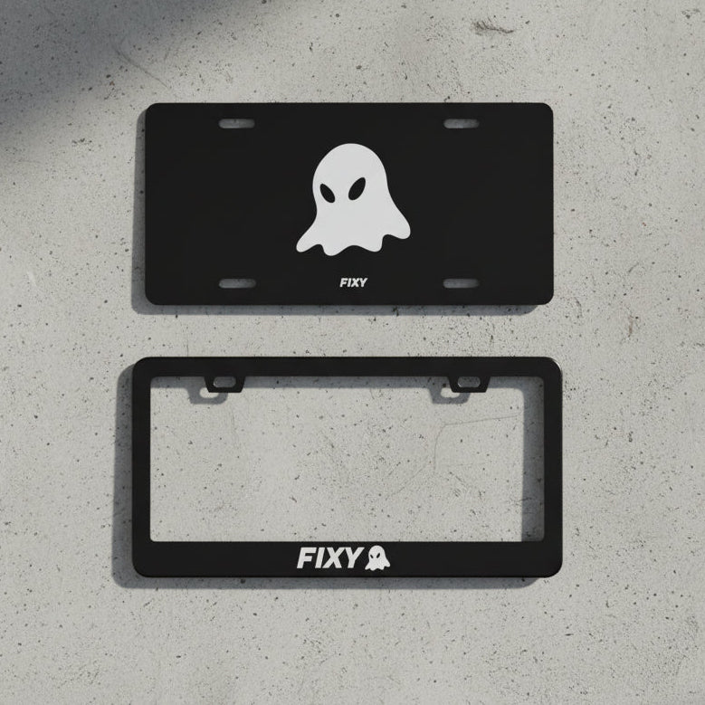 Two black license plate frames with ghost design and 'FIXY' branding on a wooden surface.