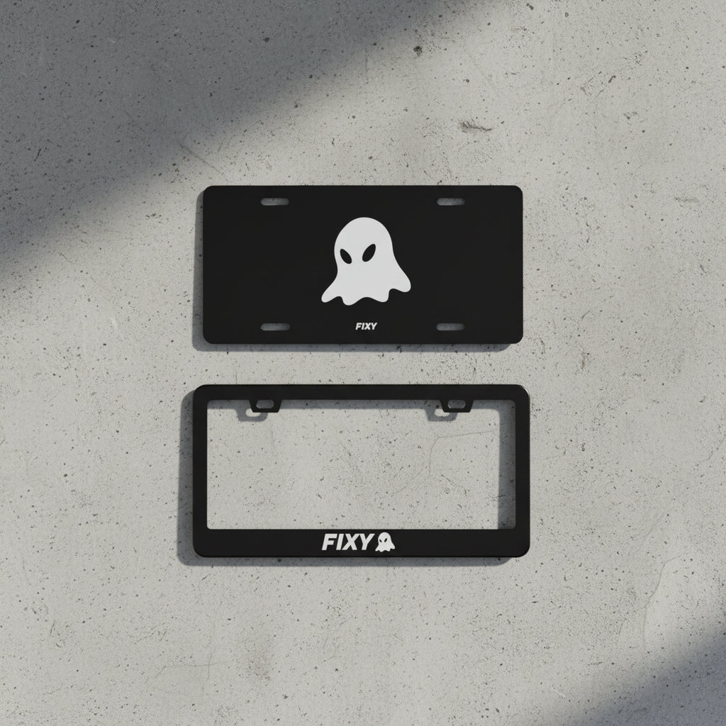 Two black license plate frames with ghost design and 'FIXY' branding on a wooden surface.