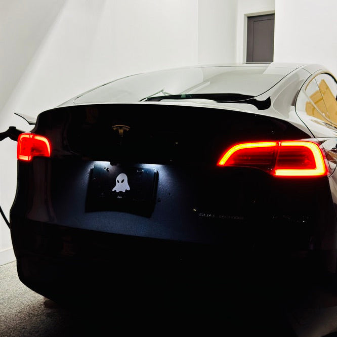 Back view of a car with illuminated taillights in a garage.