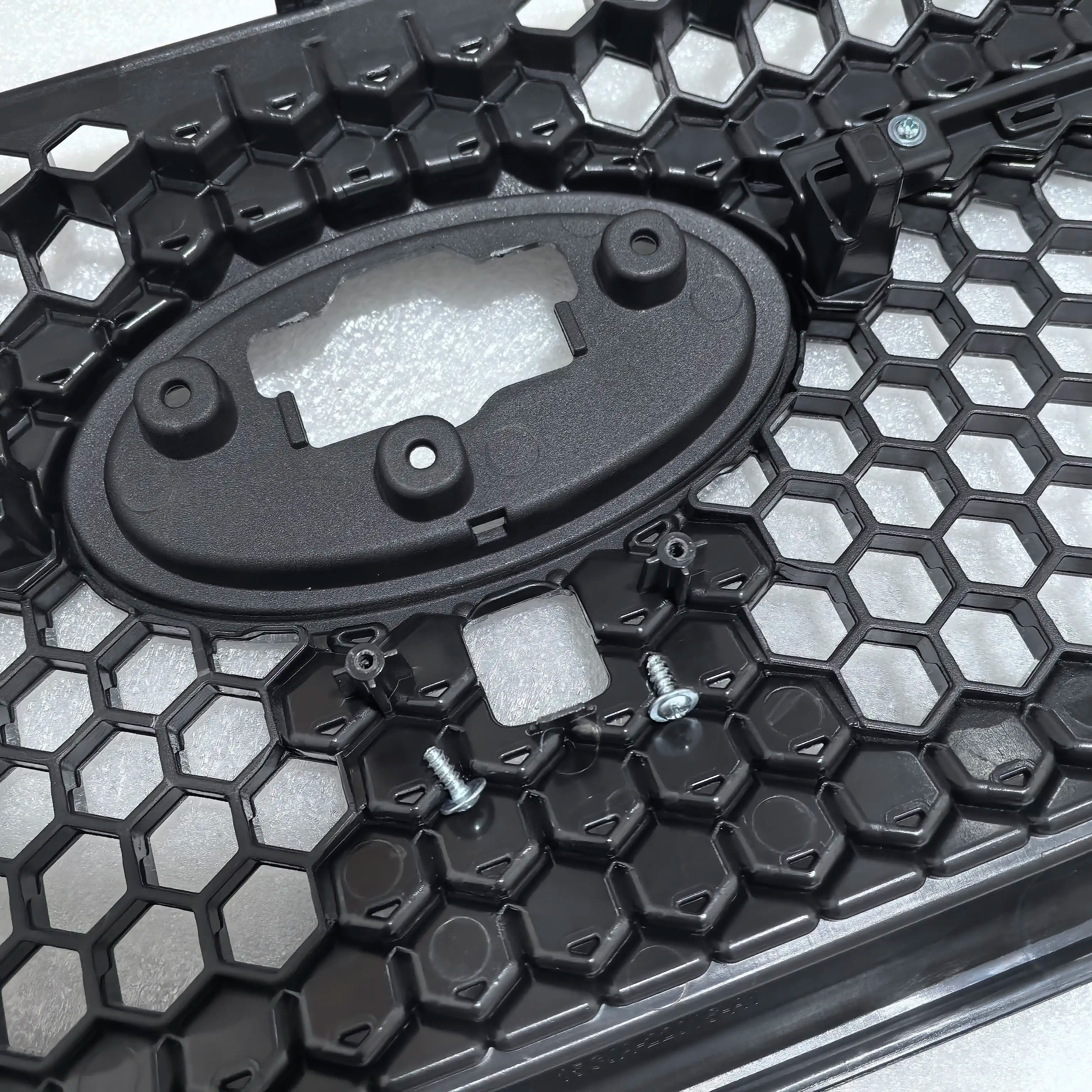Close-up of a textured black surface with hexagonal patterns and a central oval component.