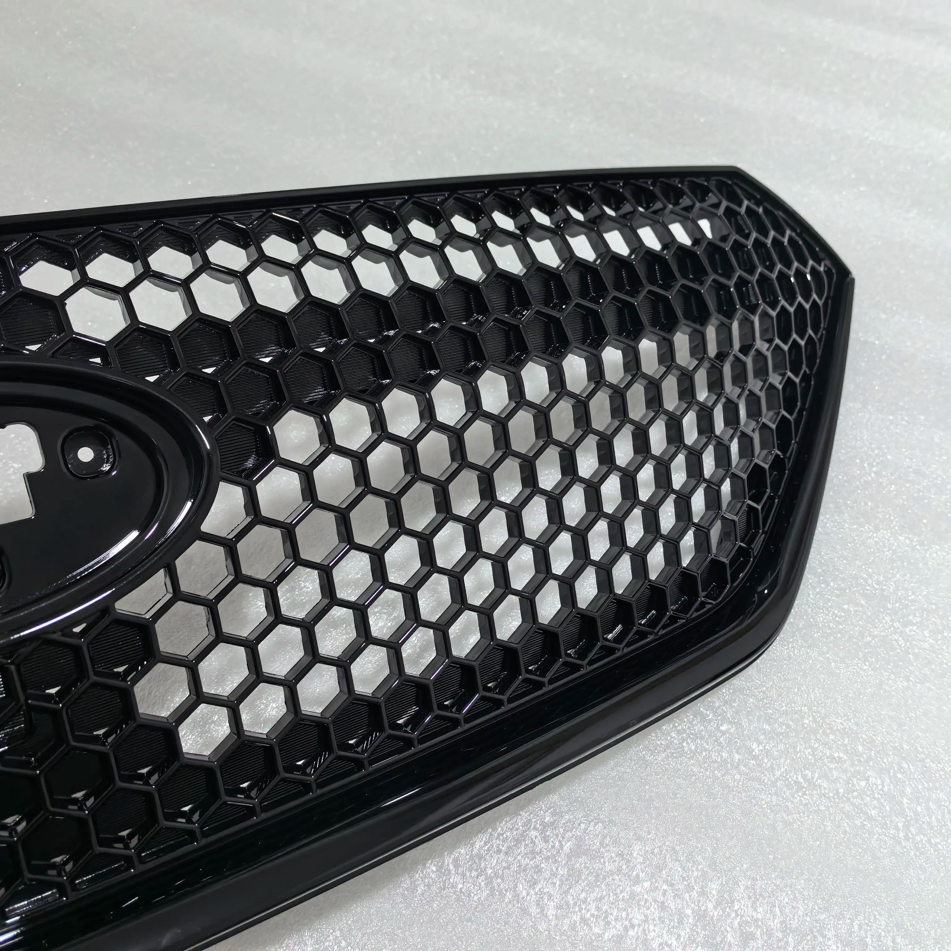 Close-up of a black honeycomb car grille on a light gray background