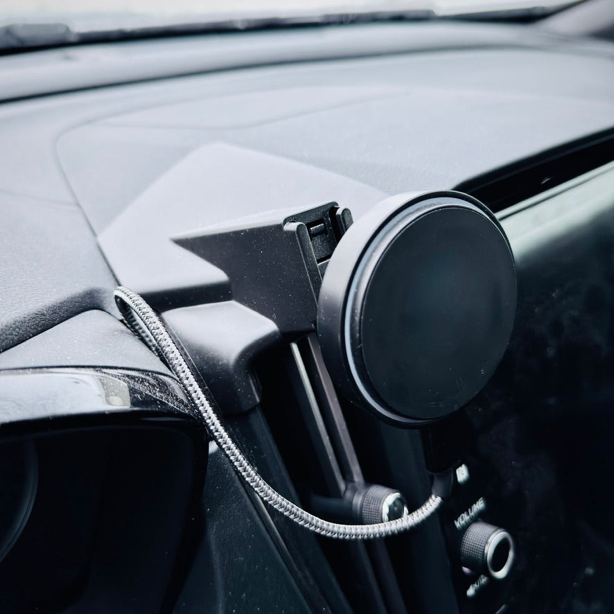 Car wireless charger holder attached to a car's air vent with a black circular diffuser.