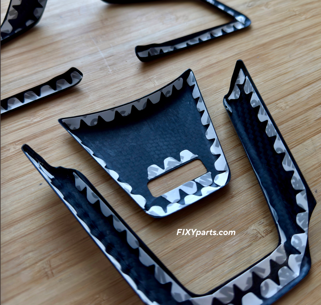Black and white shark fin-shaped parts on a wooden surface with 'FIXYparts.com' branding.