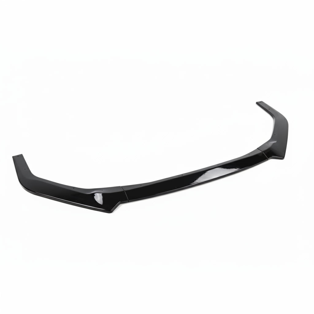 A glossy black automotive body trim piece, likely a lip spoiler or lower trim molding, displayed on a gray textured mat with a white fabric backdrop.