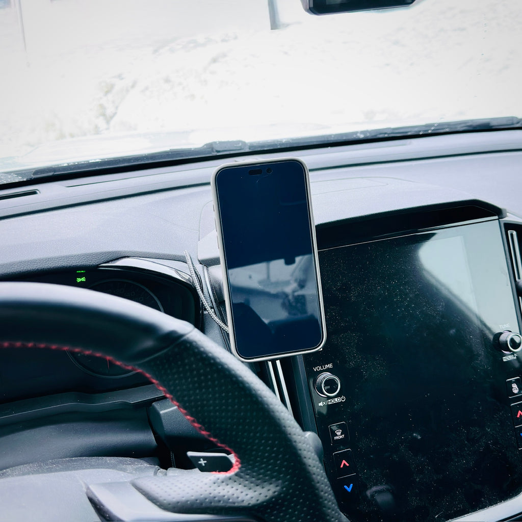 Phone mounted on a car dashboard with steering wheel and instrument panel in view