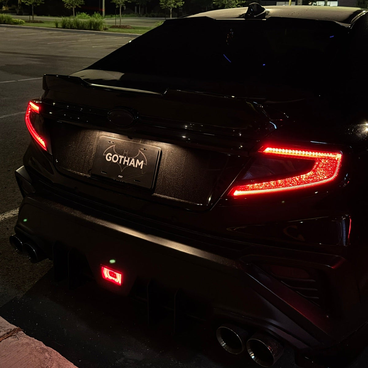 A black Hyundai Santa Fe with a custom dark tinted wrap and a 'GOTHAM' license plate frame, photographed from the rear at night in an outdoor parking lot with streetlights.