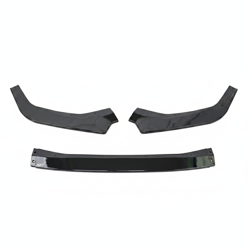 Three glossy black automotive body trim pieces, including two curved upper pieces and one longer horizontal piece, laid out on a gray textured surface with a white sheet at the top.