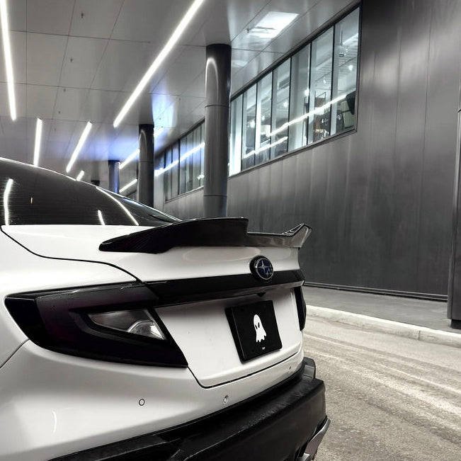White car with black roof spoiler in a modern indoor setting