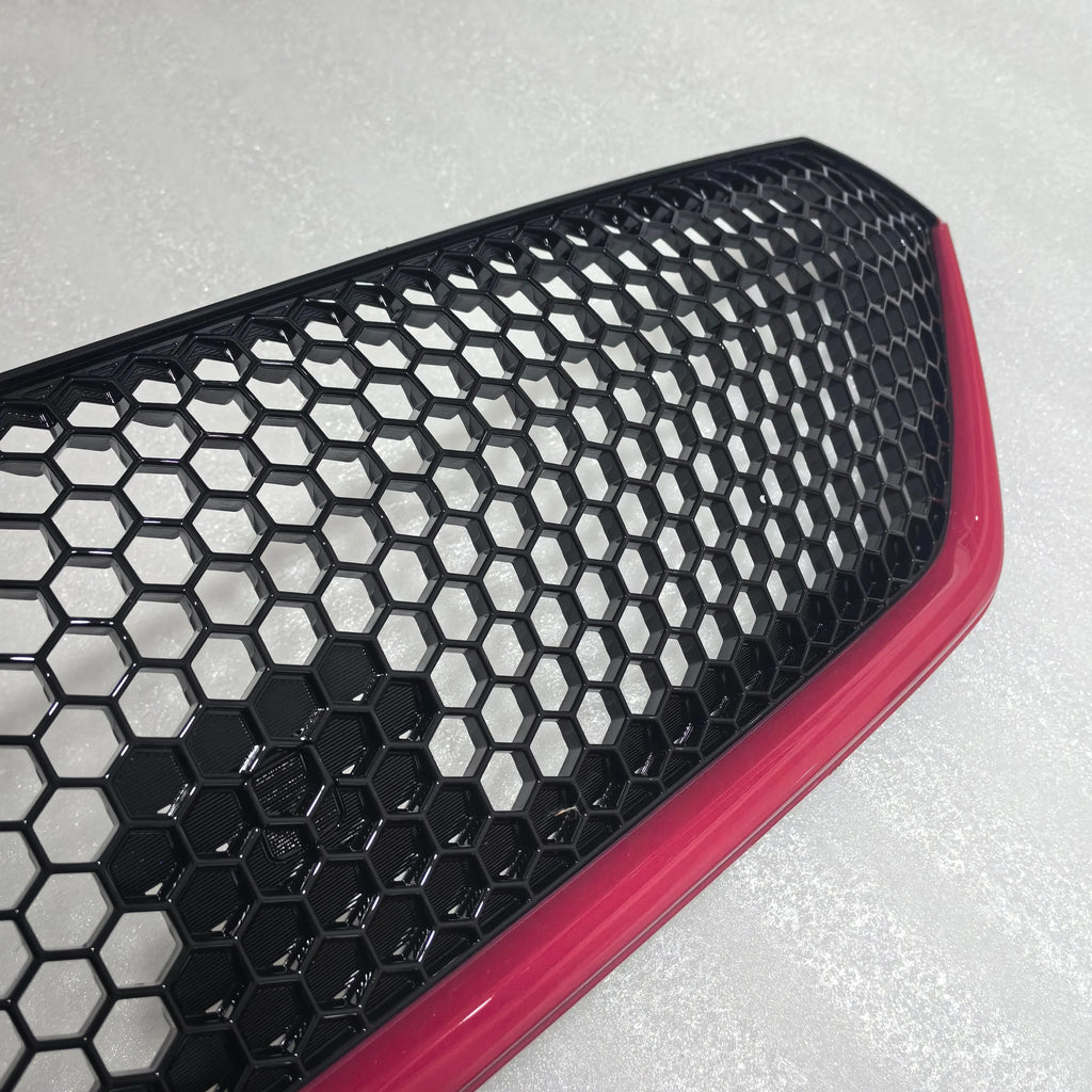 Close-up of a car grille with honeycomb pattern and red border on a white background
