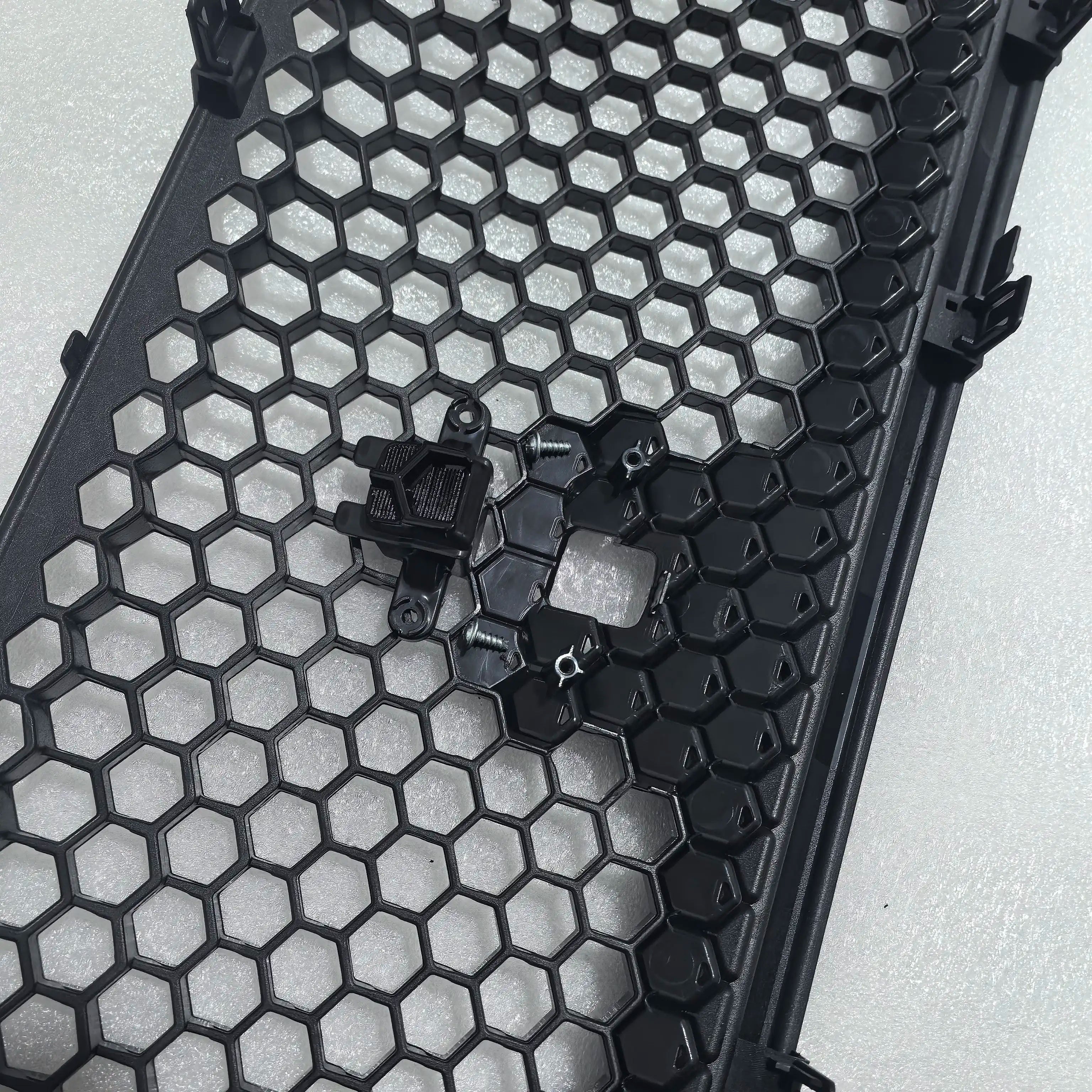 Close-up of a honeycomb-patterned black metal grid on a light gray background
